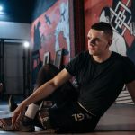 A young man stretches on the gym floor, emphasizing fitness and exercise in an urban environment.